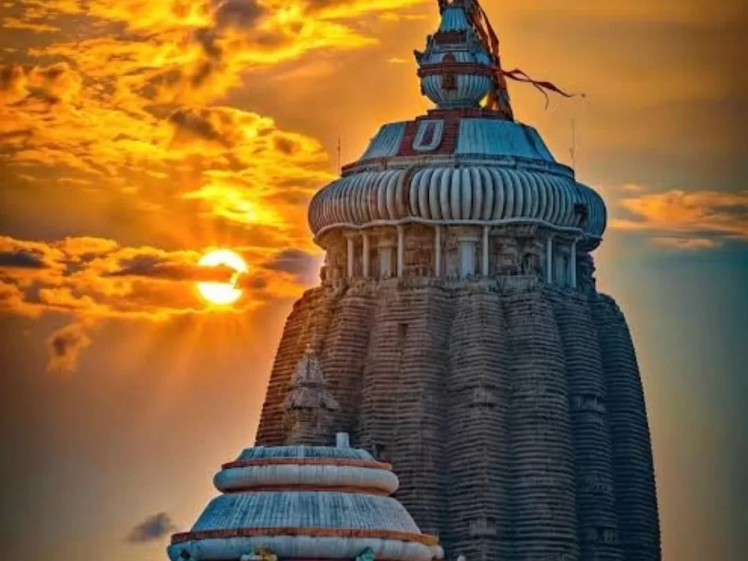 Shree Jagannath Temple vimana at Puri during sunset, featuring Neelachakra flag, golden sun rays, white sub-temple, perfect spiritual experience with Odisha Puri tour package.
