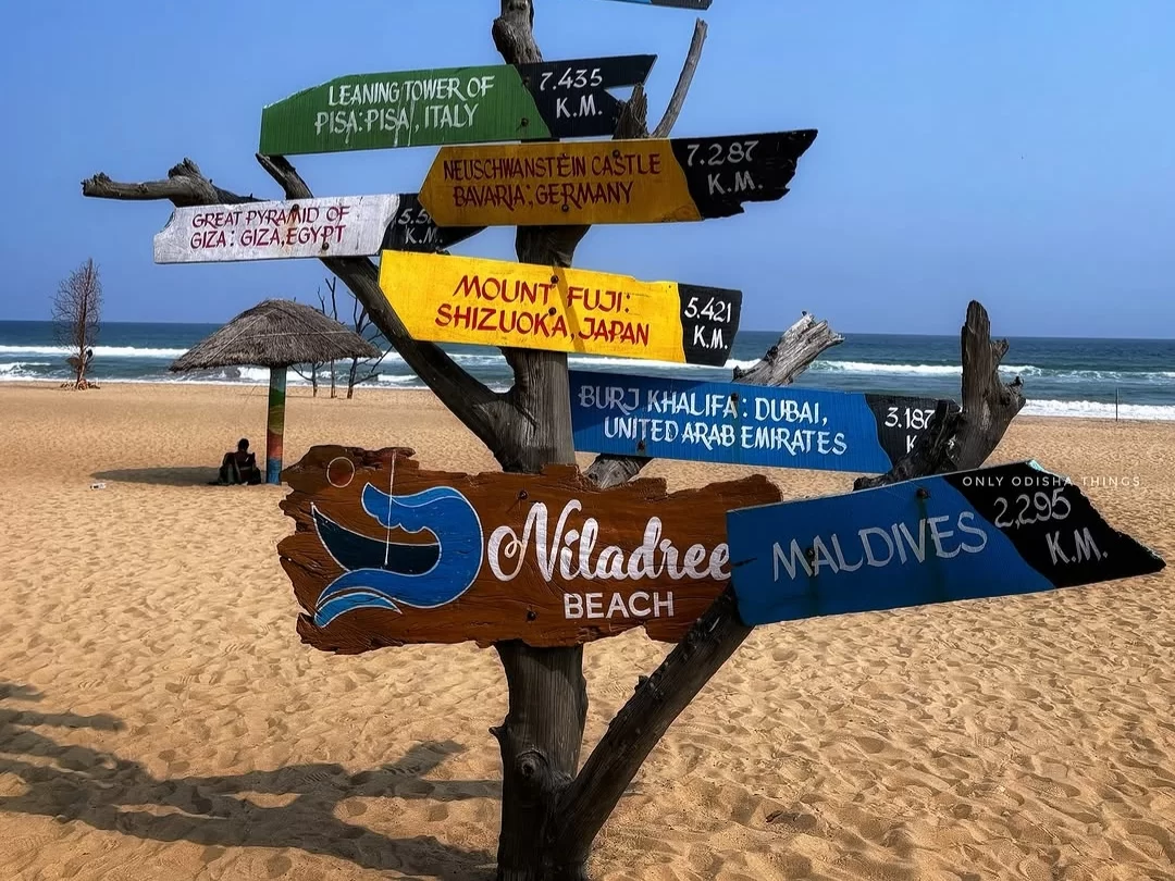 Puri Beach Odisha iconic distance signpost tree featuring Niladree Beach Maldives 2.95K km, Burj Khalifa UAE 3.57K km, Mount Fuji Japan 5.41K km, Great Pyramid Egypt, Leaning Tower Italy against Bay Bengal golden sands, perfect Jagannath world landmark to