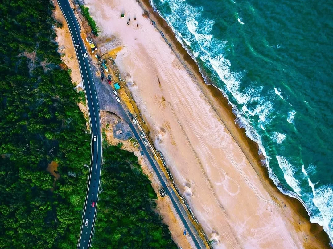 Puri Konark Marine Drive Odisha drone aerial crashing waves golden beach highway palms, scenic coastal road construction turquoise sea, perfect beach drive sunset paradise package.