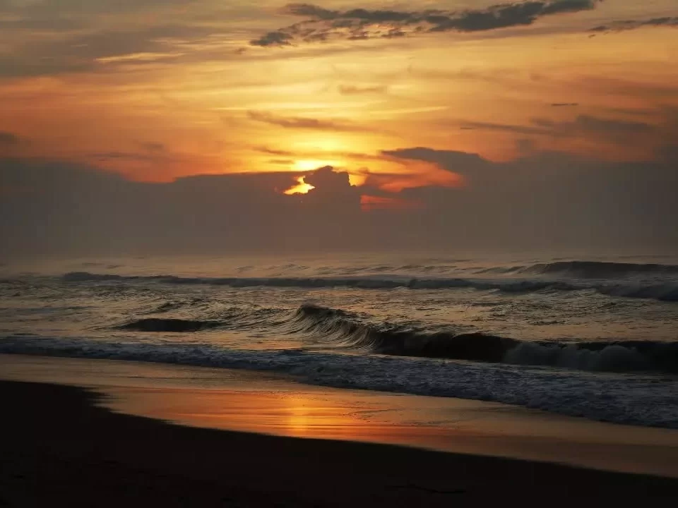 Chandrabhaga Beach Odisha during golden sunset, featuring orange sun waves sandy shore misty horizon, perfect beach experience for Konark Chandrabhaga tour package.