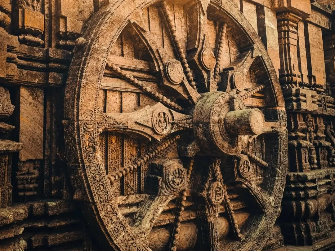 Chariot wheel at Konark Sun Temple Odisha during golden hour, featuring intricate stone carvings, spokes, pillars, perfect heritage experience Odisha tour package. 