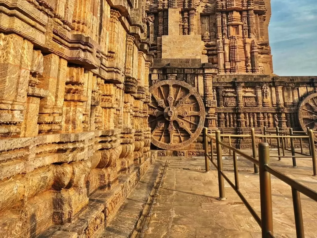 Chariot wheels at Konark Sun Temple Odisha during golden hour, featuring intricate stone carvings, pillars, railings, perfect heritage experience Odisha tour package.