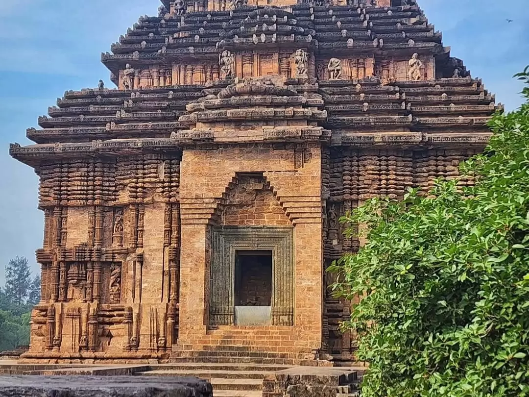 Jagamohana entrance at Konark Sun Temple Odisha during clear skies, featuring stone shikhara tower, carved pillars, greenery, perfect heritage experience Odisha tour package.
