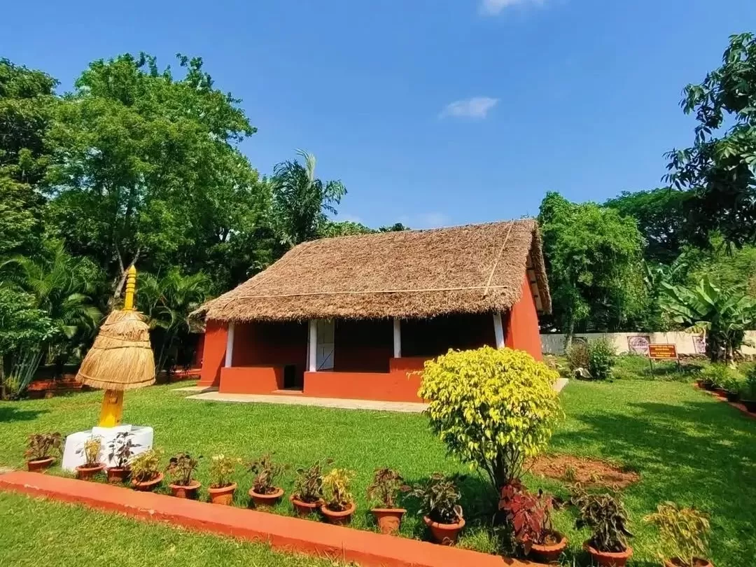 Odisha State Tribal Museum Bhubaneswar Chuktia Bhunjia red thatched hut yellow umbrella trees lush garden, perfect Odisha tribal heritage culture tour package.