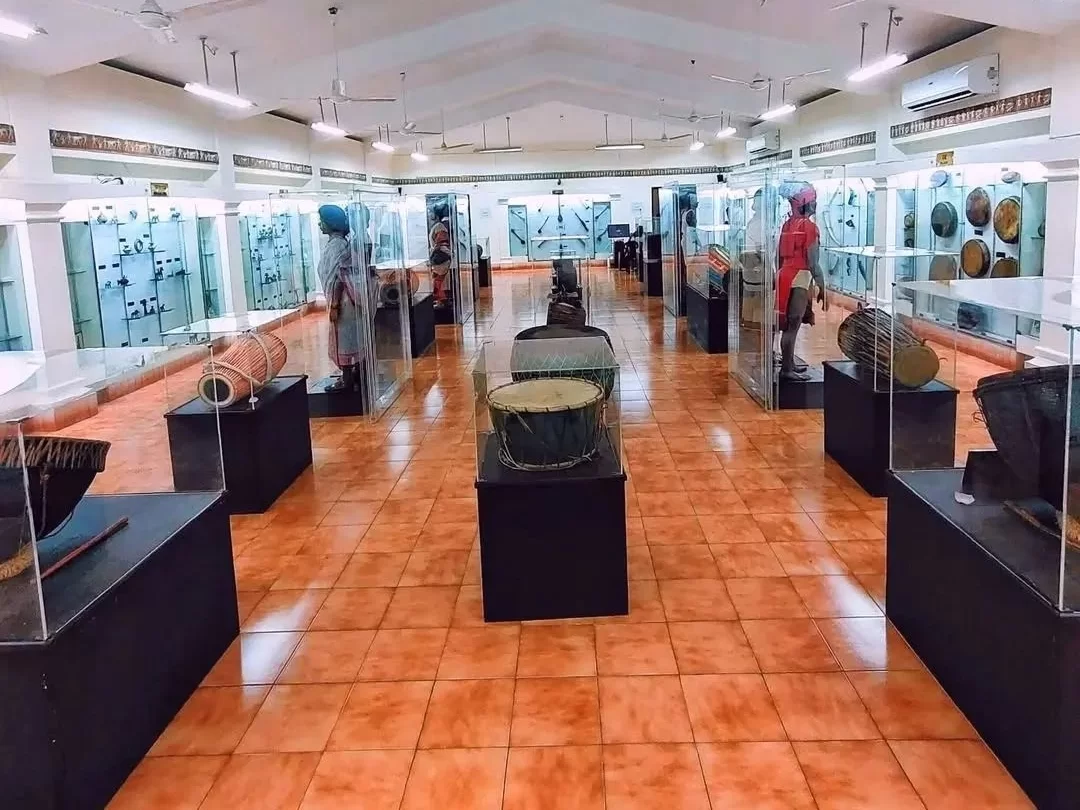 Odisha State Tribal Museum Bhubaneswar Gallery 5 musical instruments drums cymbals tribal figures orange floor display, perfect Odisha tribal heritage culture tour package.