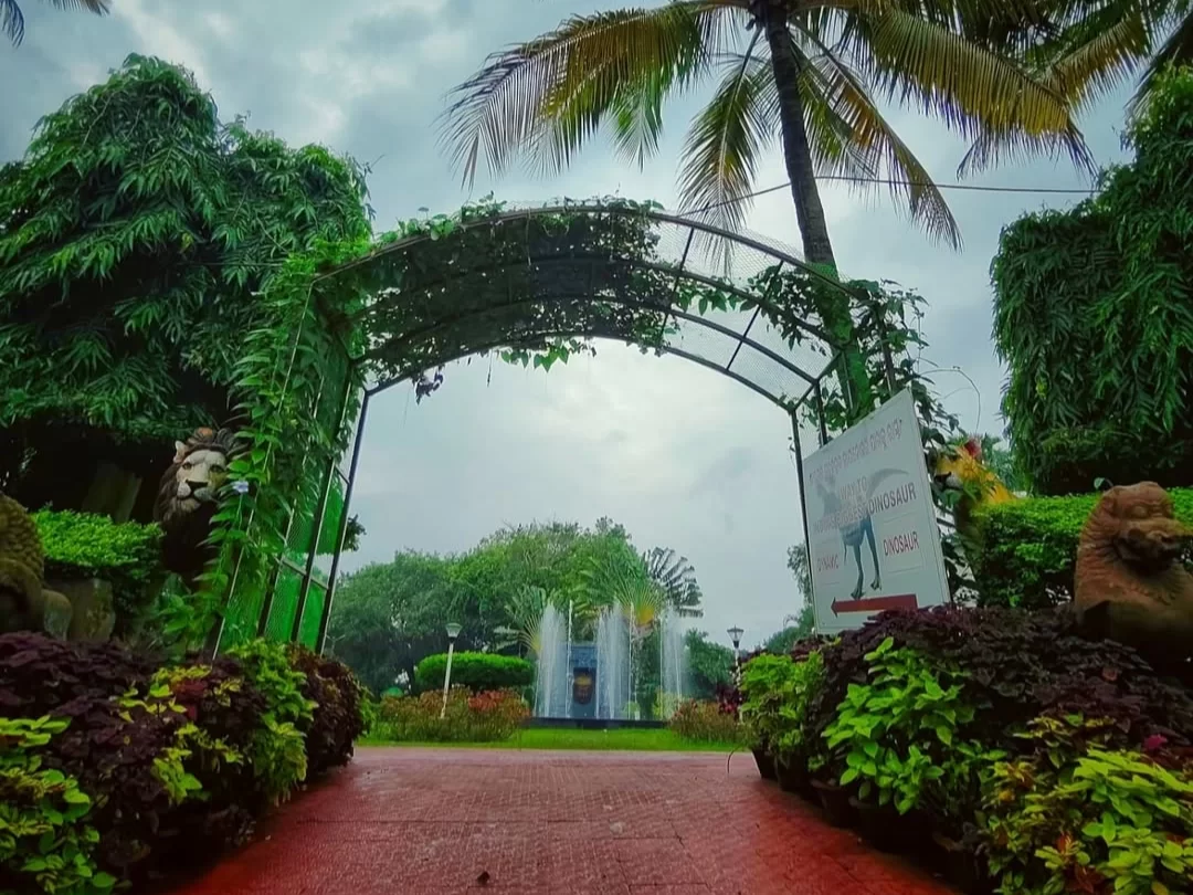 Odisha State Tribal Museum Bhubaneswar lush garden entrance vine arch lion statues fountain palms red pathway, perfect Odisha tribal heritage culture tour package. 