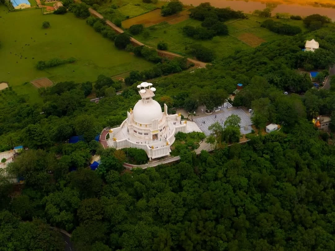 Dhauli Shanti Stupa at Bhubaneswar during golden hour, featuring white dome amid green fields, perfect heritage Bhubaneswar tour package.