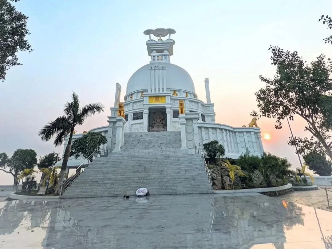 Dhauli Shanti Stupa at Bhubaneswar during sunset, featuring lion statues and dome reflections, perfect heritage Bhubaneswar tour package.