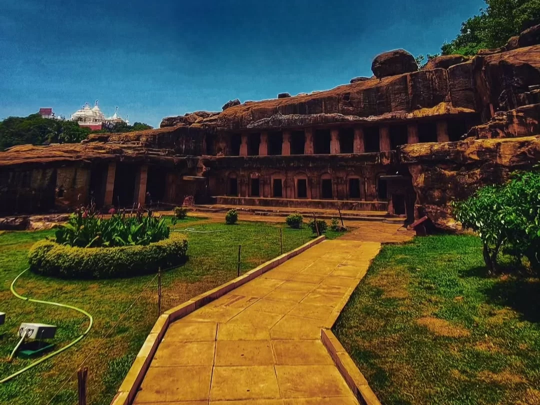 Udayagiri Caves Odisha panoramic rock-cut facade multi-chamber complex landscaped garden pathway Jain temple blue sky, perfect Bhubaneswar heritage tour package.