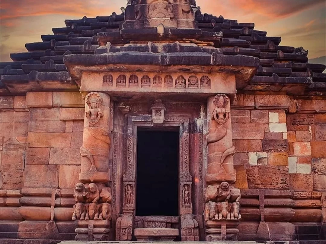 Rajarani Temple Bhubaneswar entrance dwarpalas lion guardians red sandstone sunset orange sky intricate carvings, perfect Odisha Kalinga heritage tour package.