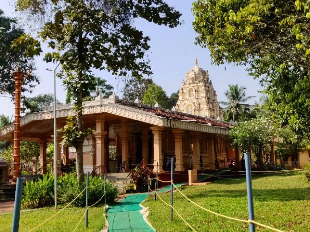 Classic Tirupati Balaji Temple North Goa showcasing tall gopuram and pillared hall amid trees, with green lawns and pathway, perfect heritage spiritual site with Goa tour package. 