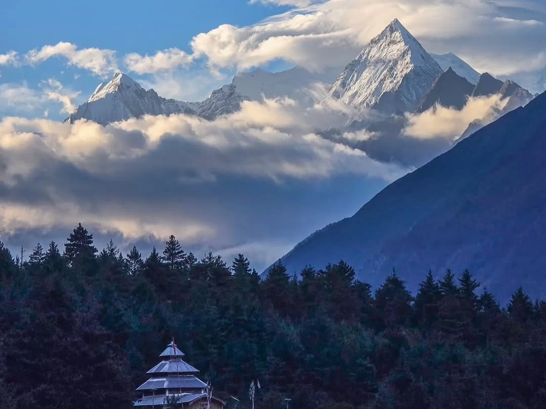 Pagoda temple at Adi Kailash during partly cloudy day, featuring snowy Himalayan peaks and pine forest, perfect spiritual Uttarakhand tour package.