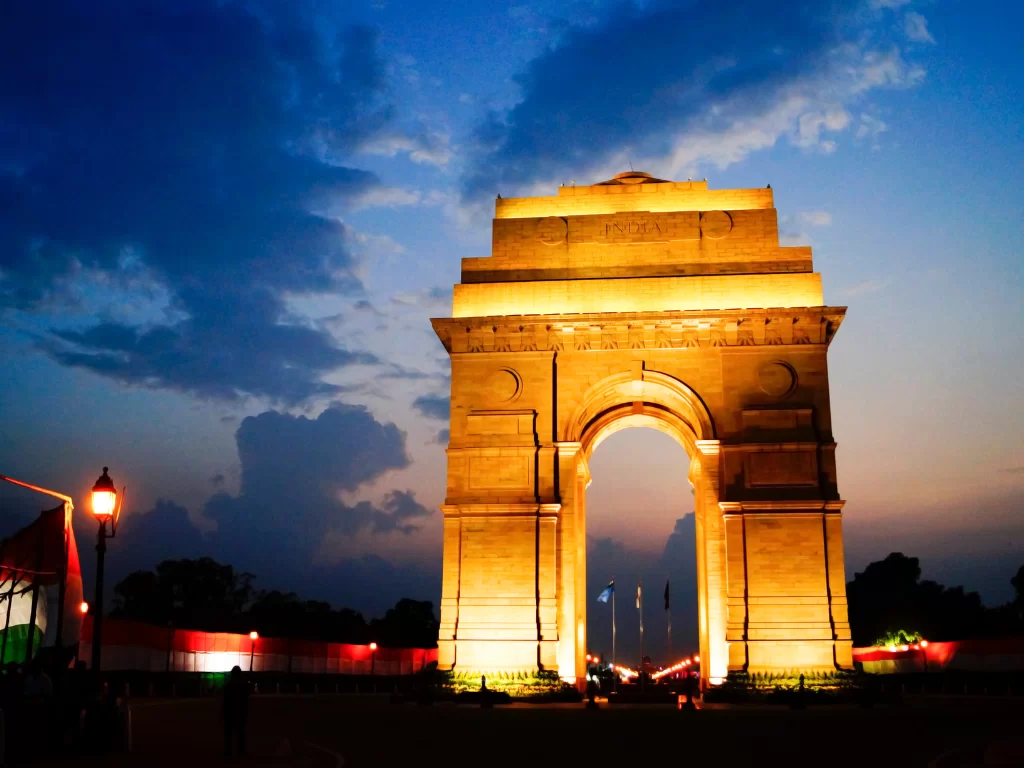 India Gate, New Delhi – grand war memorial arch beautifully illuminated against a blue evening sky, iconic landmark and must-visit stop on Delhi city tour packages.