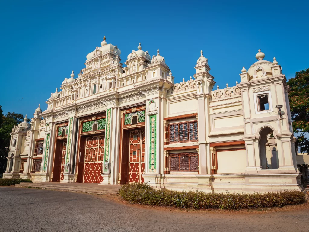 Jaganmohan Palace in Mysore during sunny daytime, featuring ornate ivory facade and arched entrance, perfect heritage Karnataka tour package
