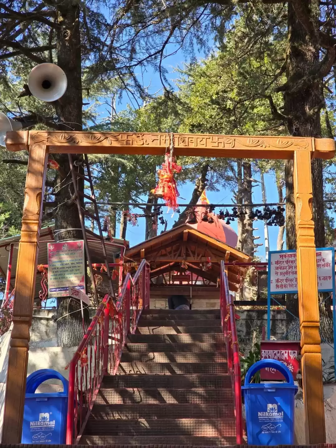 Entrance gate and stairway leading to Mukteshwar Temple surrounded by tall deodar trees in Mukteshwar, Uttarakhand, a peaceful hill destination featured in Uttarakhand tour packages.