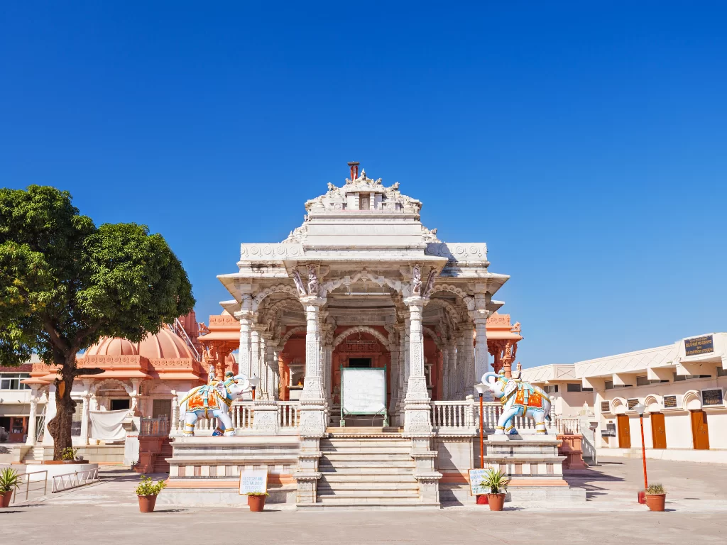 Mandavgarh Suparshvnath Jain Temple at Mandu under clear skies, featuring ornate marble shikhara and elephant statues, perfect heritage experience with Madhya Pradesh tour packages.