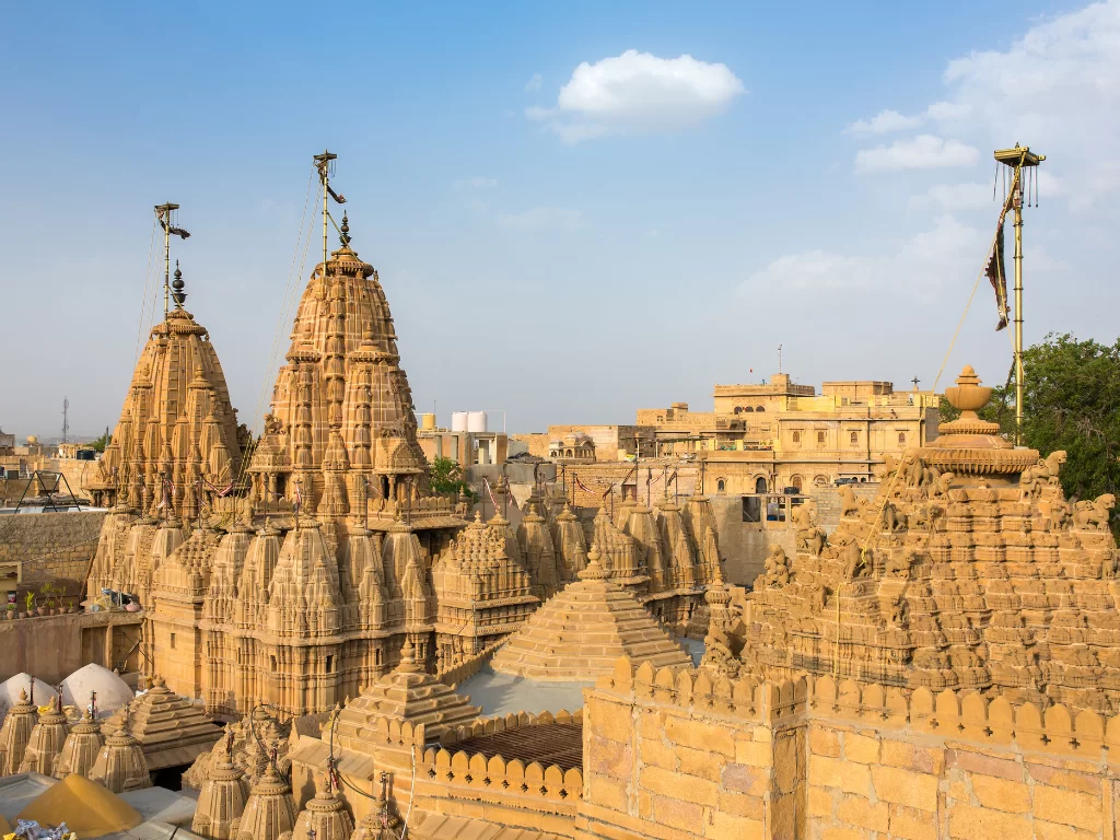 Jain temple complex at Jaisalmer during clear sky, featuring multiple shikharas & golden domes, perfect romantic experience Rajasthan tour packages. 