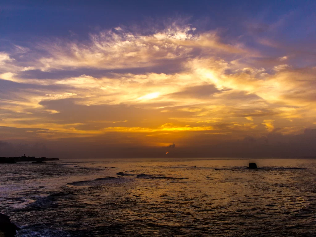 Dramatic sunset at Jallandhar Beach Diu during golden hour, featuring rocky cliffs and fiery clouds, perfect romantic Diu tour package.