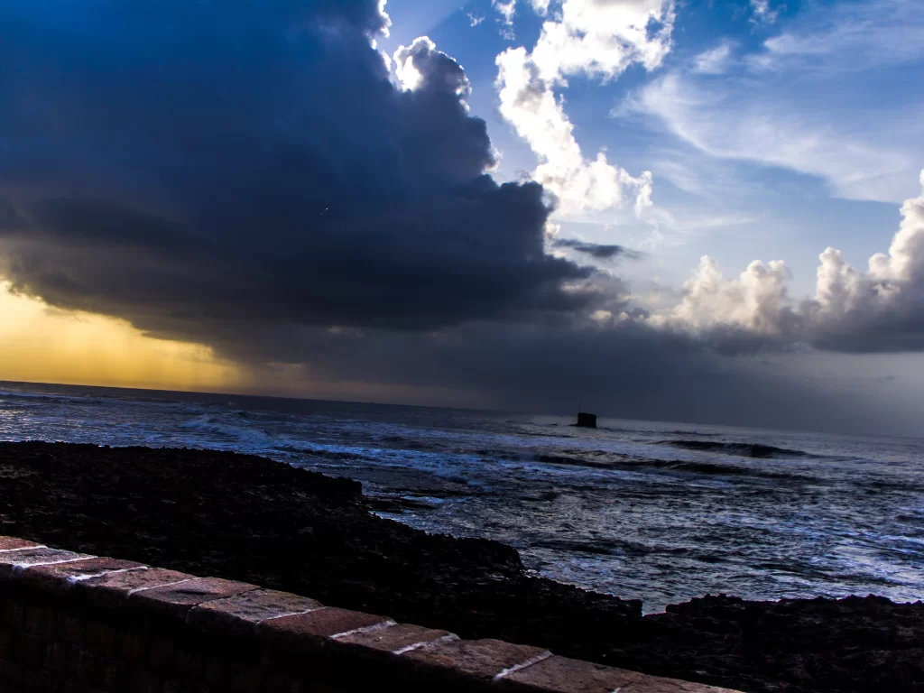 Dramatic sunset at Jallandhar Beach Diu during golden hour, featuring dramatic clouds and rocky outcrops, perfect romantic Diu tour package.