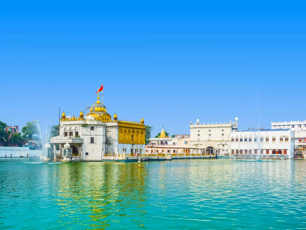 Historic Jallianwala Bagh at Amritsar during sunny day, featuring memorial walls, well, gardens, eternal flame, perfect heritage Amritsar  tour package.
