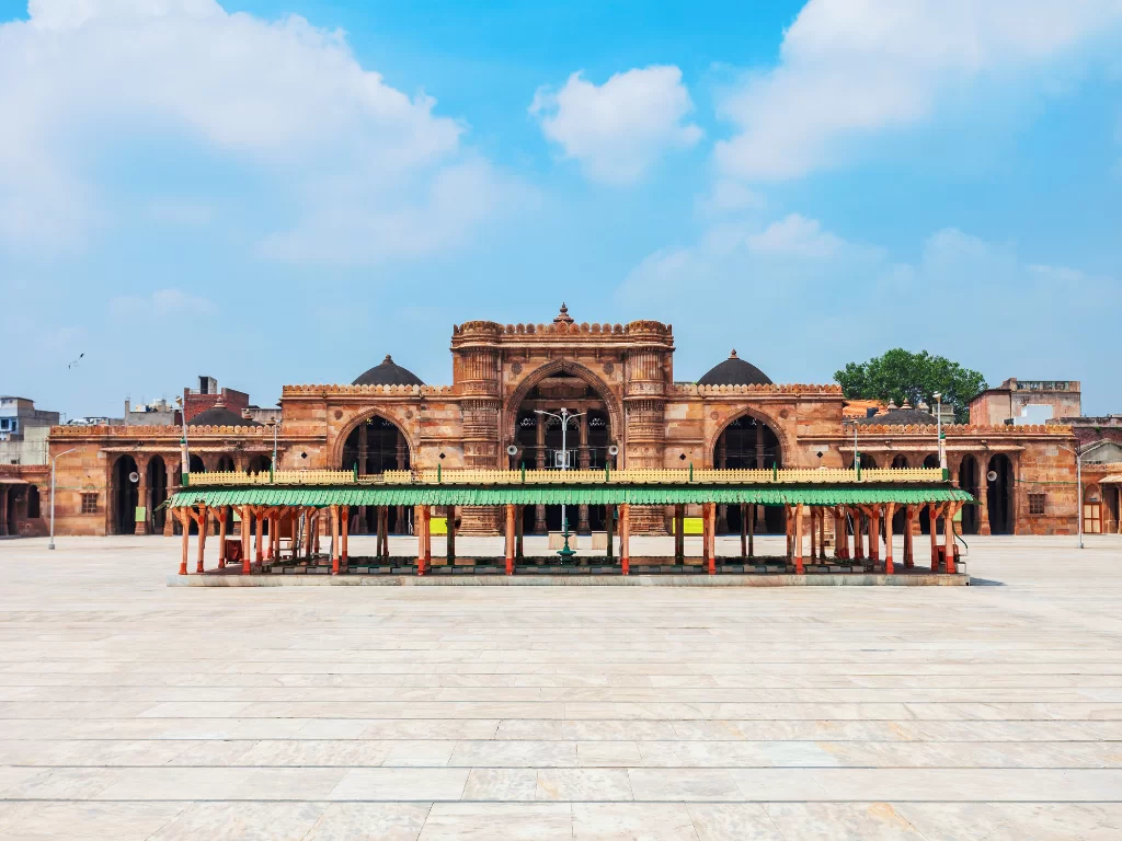 Iconic entrance at Jama Masjid Ahmedabad during daylight, featuring domes and green canopy, perfect cultural Gujarat tour package.