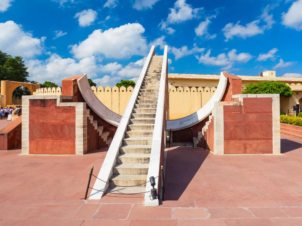 Jaipur Jantar Mantar at sunny day with blue sky, featuring massive sundial arches stairs, perfect heritage experience Rajasthan tour packages.