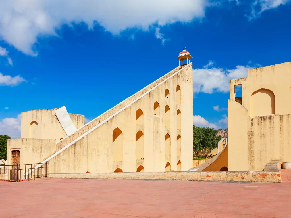 Samrat Yantra sundial at Jantar Mantar Jaipur during clear day, featuring towering triangular structure and arched walls, perfect heritage experience Rajasthan tour packages.