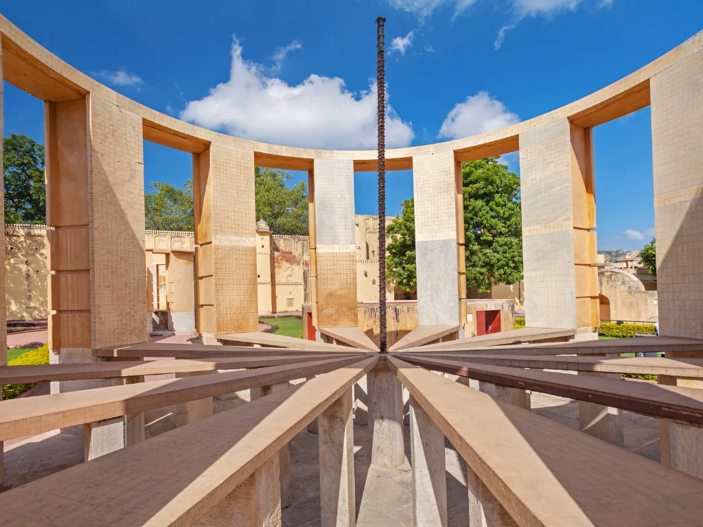 Chakra Yantra interior at Jantar Mantar Jaipur during sunny day, featuring central gnomon and arched walls, perfect heritage experience Rajasthan tour packages.