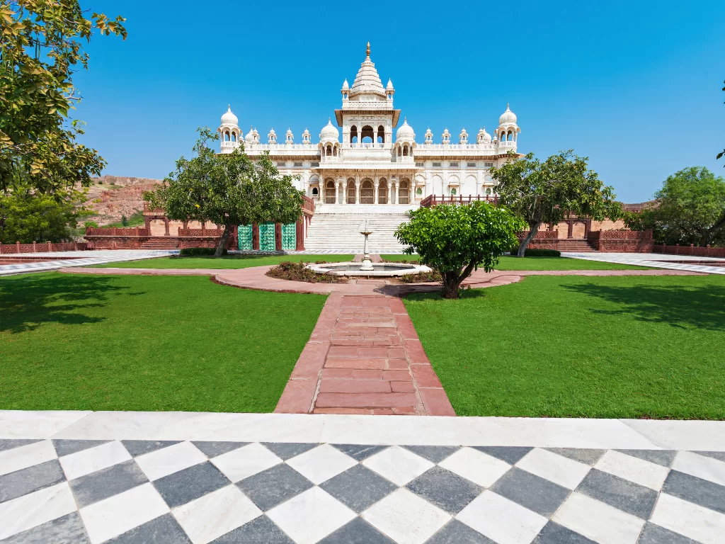 Jaswant Thada courtyard fountain trees lawns checkered marble floor distant dome blue sky backdrop, perfect Rajasthan tour packages. 