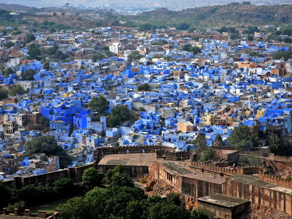 Panoramic Blue City Jodhpur from fort during golden hour, featuring blue rooftops and hills, perfect romantic experience in Rajasthan tour package. 