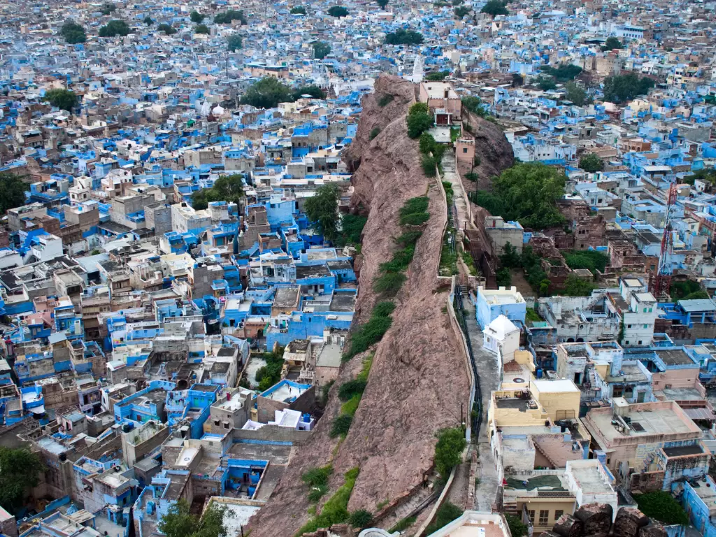 Mehrangarh Fort overlooking Jodhpur's Blue City during misty dawn, featuring blue houses and rocky ridge, perfect adventure experience in Rajasthan tour package. 