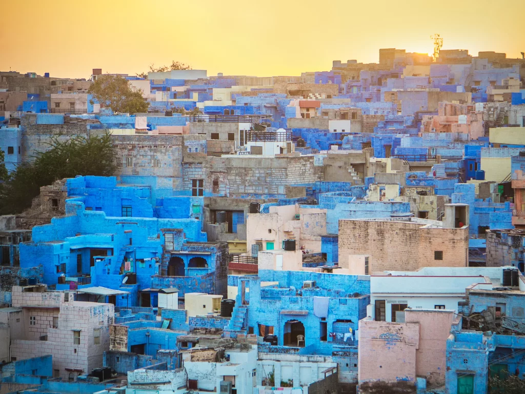 Vibrant blue houses in Jodhpur's Blue City at sunset, featuring clustered rooftops and golden hues, perfect cultural experience in Rajasthan tour package.