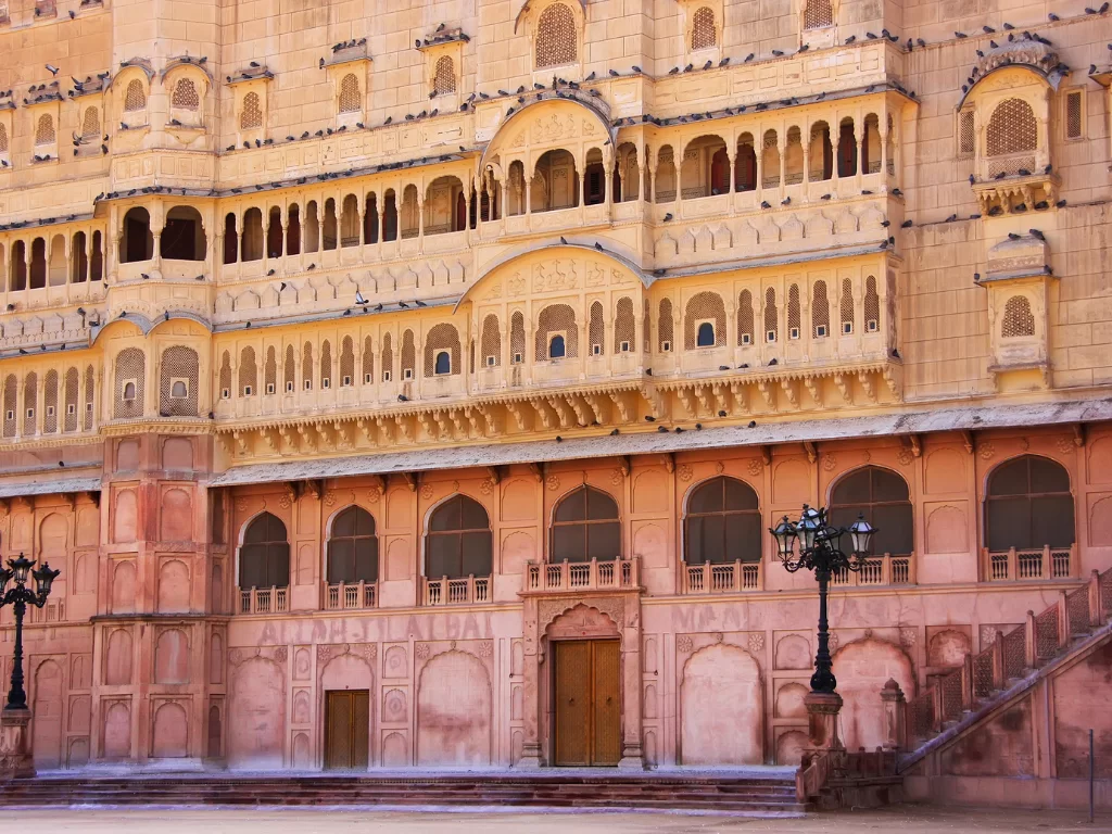 Intricate courtyard facade of Junaghar Fort in Bikaner at midday, featuring arched balconies and jharokhas, perfect Bikaner heritage tour package