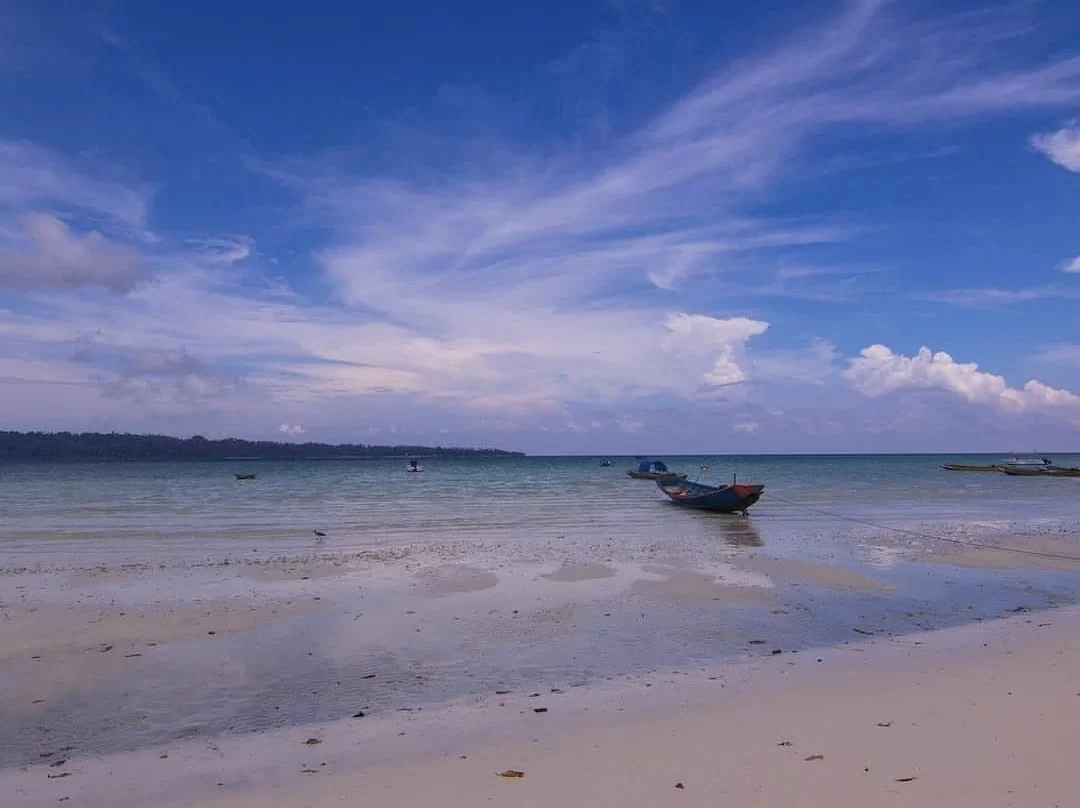 Traditional wooden boats anchored shallow turquoise waters white sandy shore distant rainforest horizon partly cloudy blue sky Kalapathar Beach Havelock Island Andaman Islands, perfect serene fishing boats sunrise eco-tourism Andaman package.