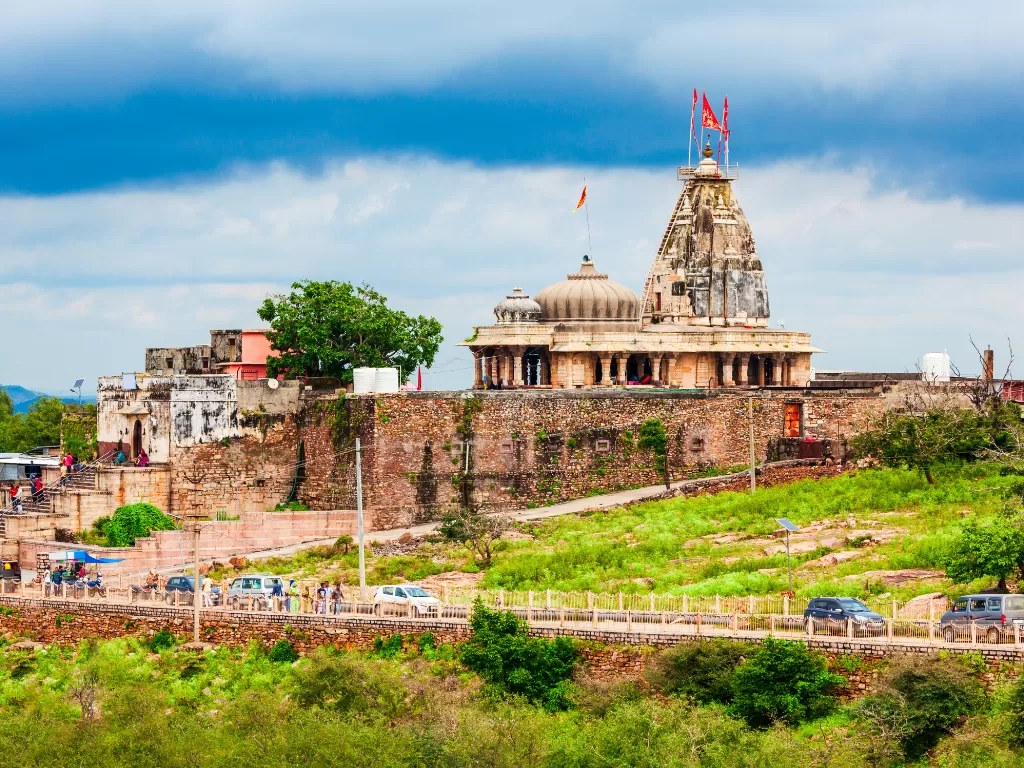 Kalika Mata Temple atop fort wall in Chittorgarh, Rajasthan under blue sky, featuring flags, dome and greenery, perfect Rajasthan tour package