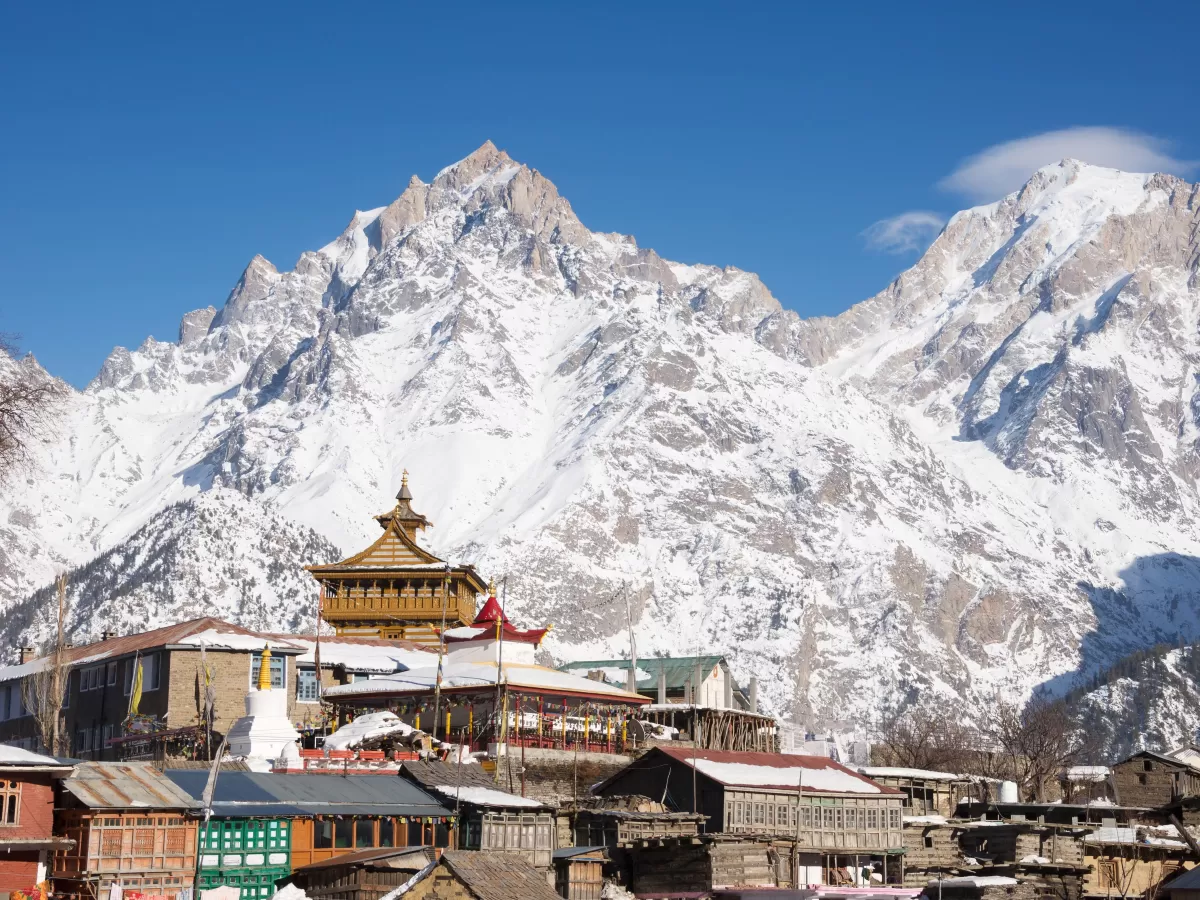 Kalpa Village Kinnaur winter panoramic, featuring golden pagoda temple colorful houses snow-capped Kinner Kailash peaks blue skies, perfect Himachal Pradesh tour packages.