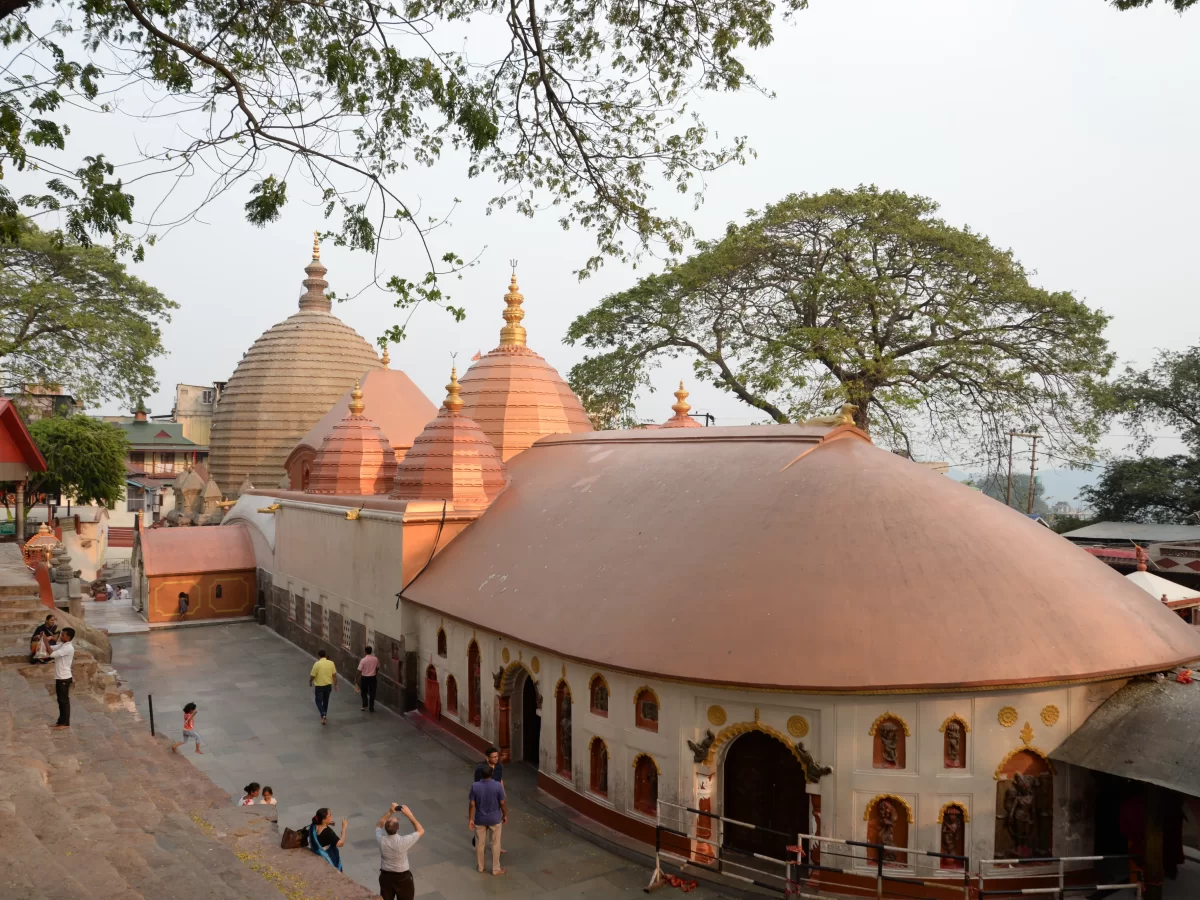 Devotees exploring Kamakhya Temple in Guwahati during soft daylight, featuring Nilachal-style domes and courtyard, perfect spiritual experience Assam tour package.