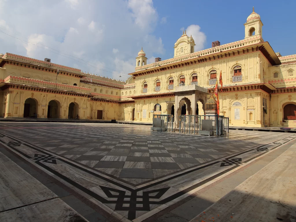 Kanak Bhawan courtyard at Ayodhya during sunny day, featuring ornate arches and flags, perfect cultural experience Uttar Pradesh Tour Packages.