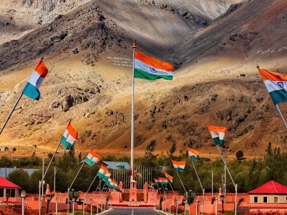 Drass War Memorial Ladakh multiple Indian flags pink pavilions central monument rugged mountains Kargil Vijay Diwas patriotic tribute Operation Vijay heroes, perfect Ladakh heritage tour package.