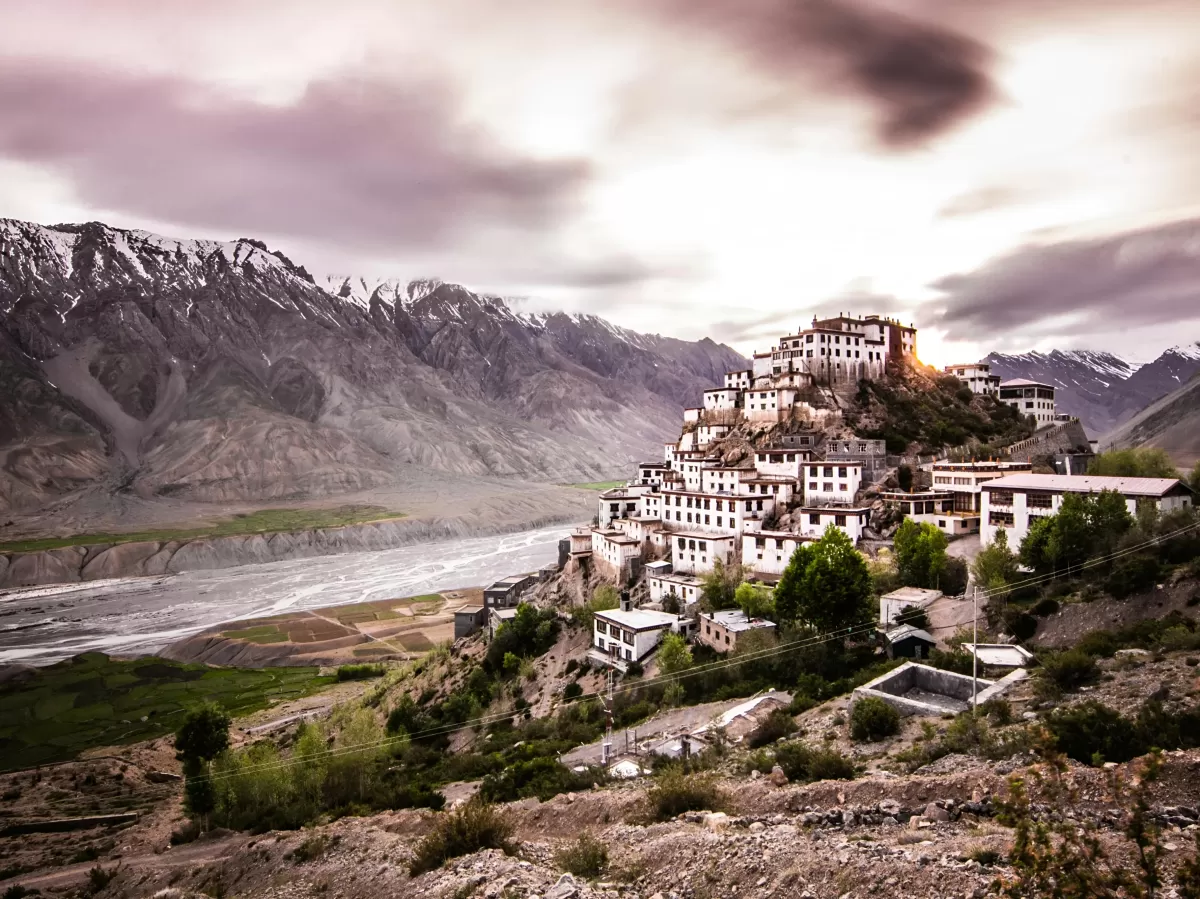 Key Monastery at Losar Spiti during twilight dusk, featuring tiered white monastery rugged mountains river valley, perfect spiritual experience Himachal Pradesh tour package.