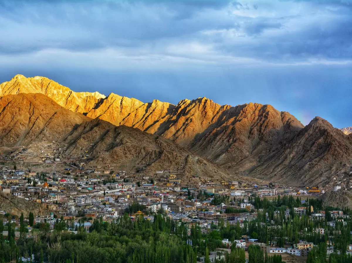 Kibber Village near Kaza during golden hour sunset, featuring village houses green trees golden brown mountains, perfect cultural experience Himachal tour package.