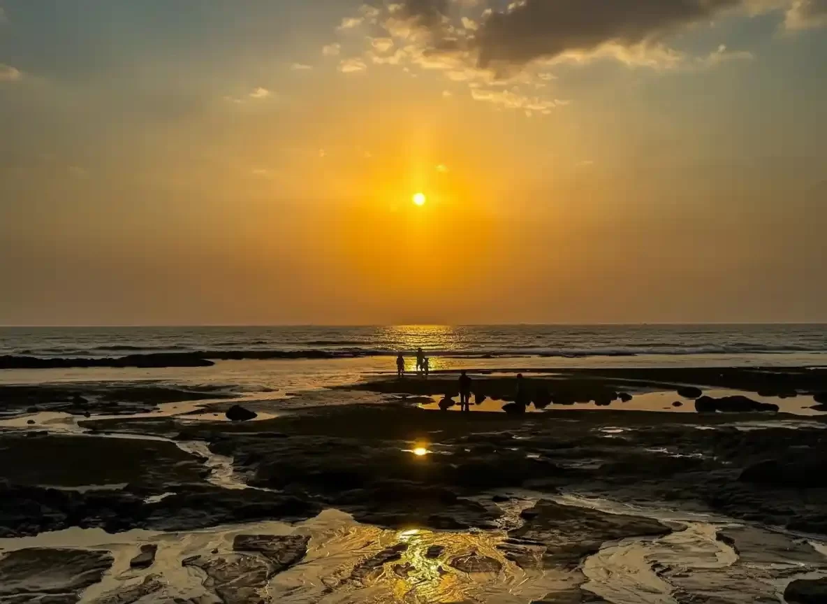 Kihim Beach serene sunset view with rocky shoreline in Maharashtra tour packages
