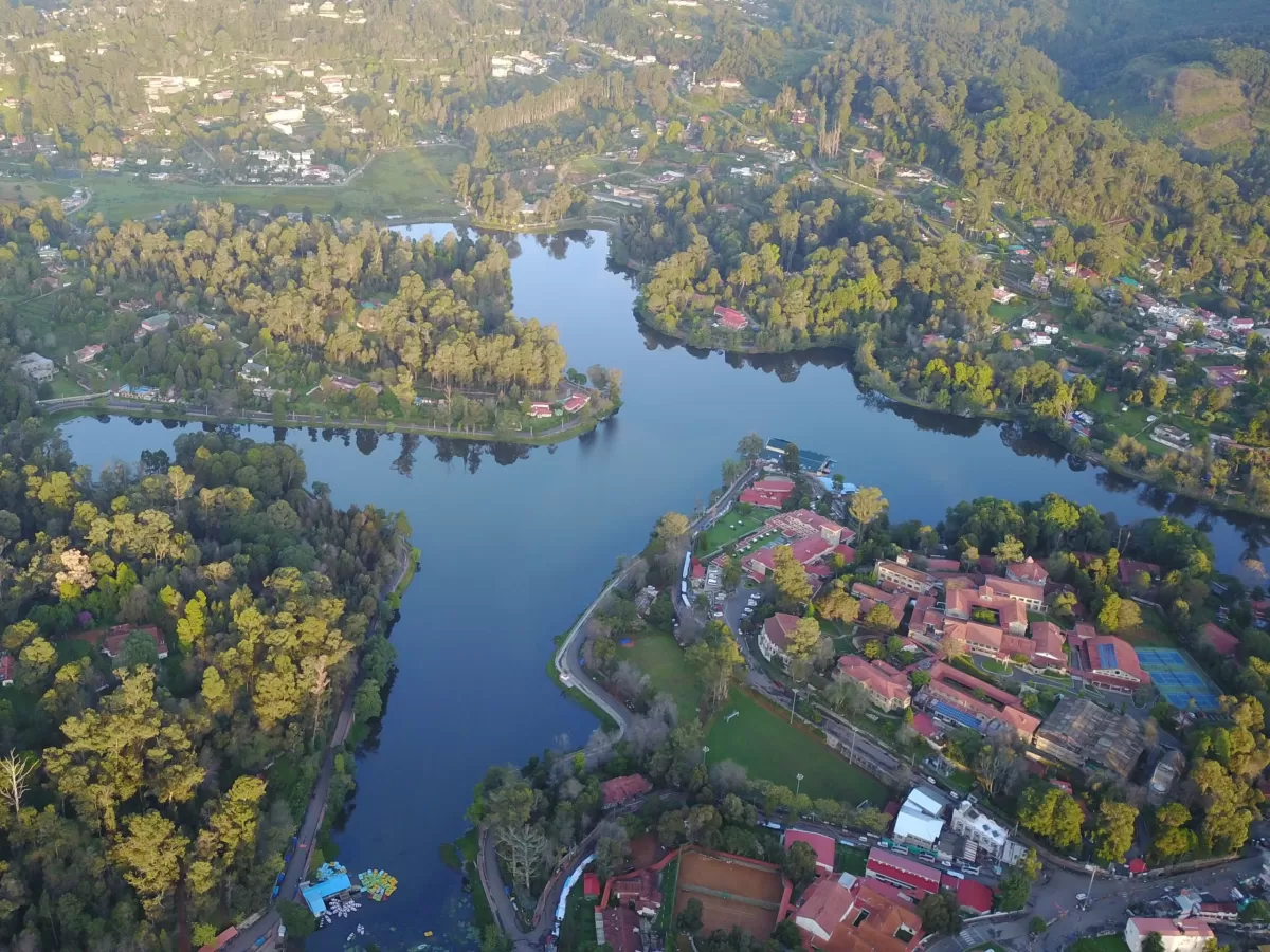Aerial view of star-shaped Kodai Lake in Kodaikanal, featuring surrounding forests, resorts and winding lakeside roads, perfect scenic Tamil Nadu tour package