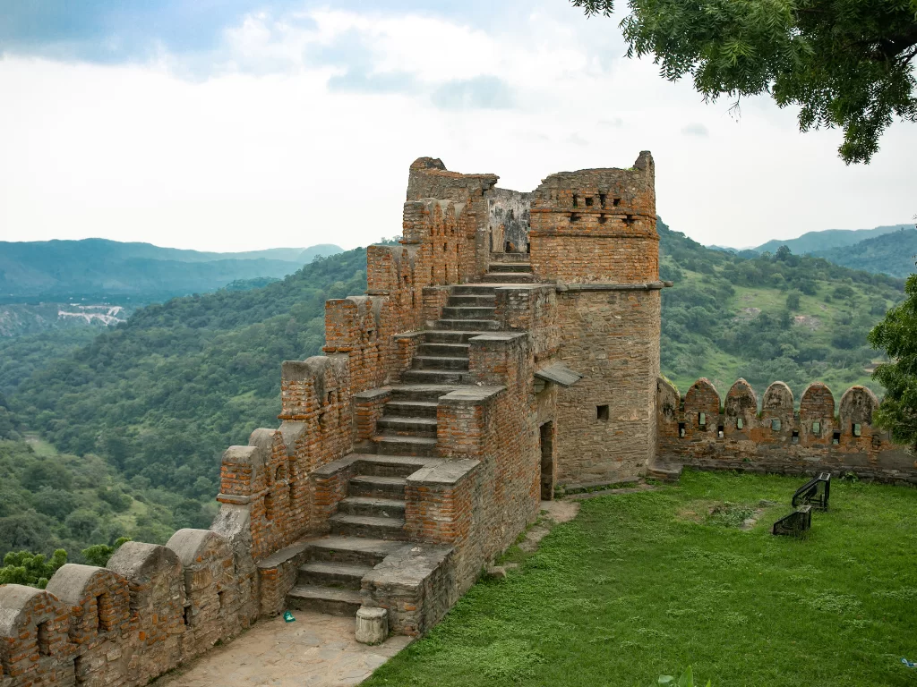Kumbhalgarh Fort ramparts during cloudy day, featuring stone bastions, steep stairs, valley views, perfect adventure experience Rajasthan tour packages. 