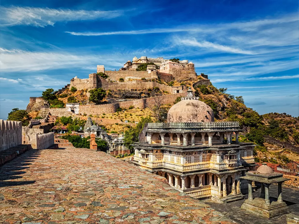Kumbhalgarh Fort during partly cloudy day, featuring tiered ramparts, dome pavilion, jharokhas, Aravalli hills, perfect adventure experience Rajasthan tour packages.