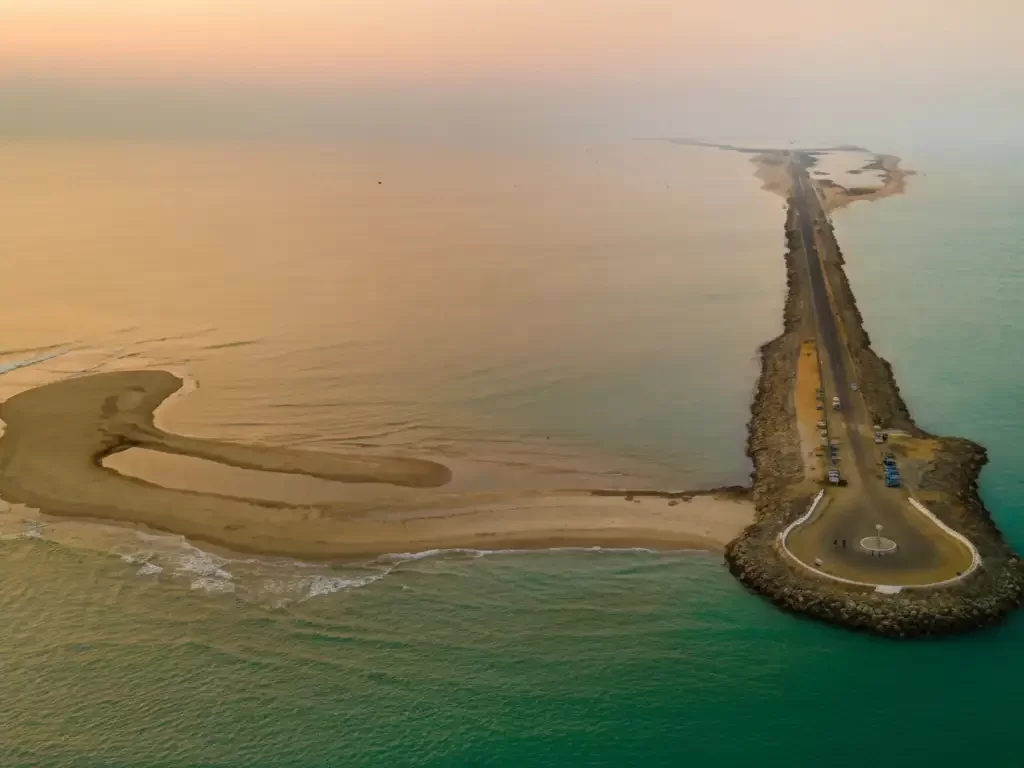 Kunthukal Beach in Rameswaram featuring turquoise shallow waters, fishing boats, and the Vivekananda Memorial Hall.