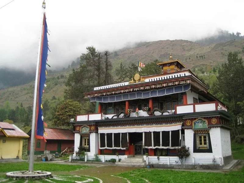 Lachung Monastery Sikkim amid misty hills and prayer flags, colorful gompa architecture, perfect cultural North Sikkim tour package.