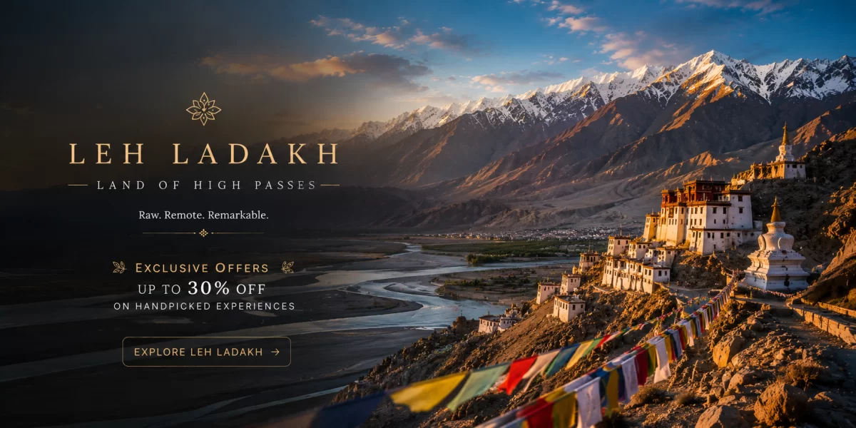 Ancient Buddhist monastery overlooking dramatic Himalayan mountains and river valleys with colorful prayer flags during golden sunset in scenic Leh Ladakh.