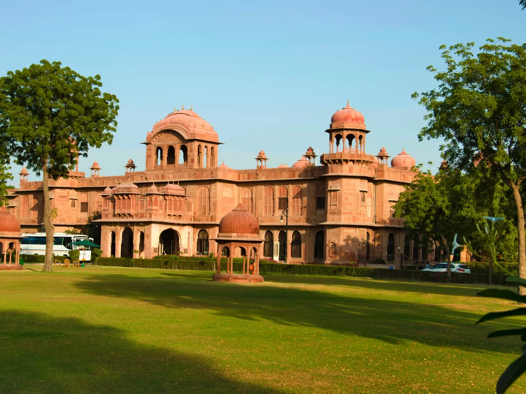 Lalgarh Fort palace view in Bikaner during daytime, featuring red sandstone domes and green lawns, perfect Bikaner heritage tour package