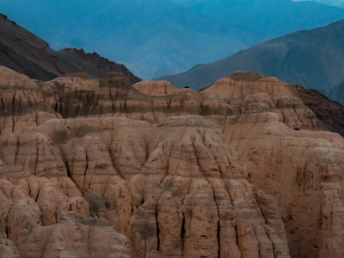 Lamayuru Moonland Ladakh dramatic eroded lunar landscape formations at twilight with layered cliffs against Himalayan mountains, iconic moonscape near Lamayuru Monastery on Leh Kargil highway in Ladak